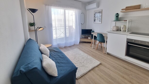 A modern living room with a sofa, a dining area, and a kitchen. - AC studio with balcony in central Arcachon (Arcachon)