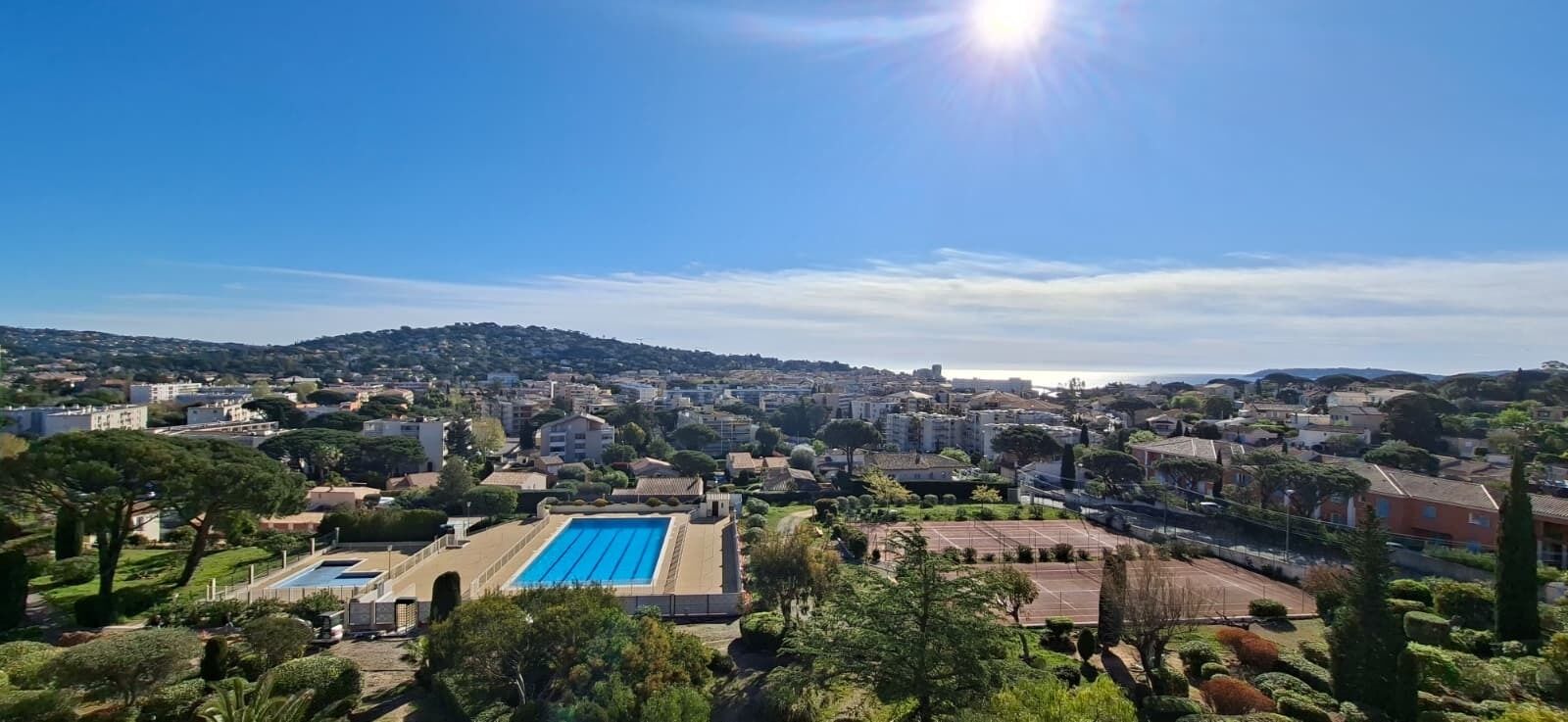 A residential area with a swimming pool, tennis courts, and houses.