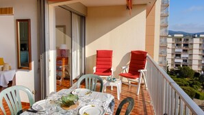Ein Balkon mit Esstisch, zwei roten Stühlen und Blick auf ein Wohngebäude.