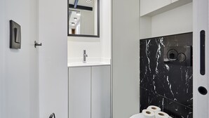 A modern bathroom with a white vanity, a black marble shower enclosure, and a mirror above the sink. - Charming Duplex Loft - Paris City Center (Paris)