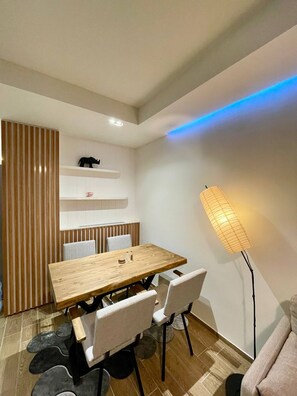A modern dining area with a wooden table, white chairs, a striped partition, a shelf with decorative items, and a floor lamp. - Unique Andcosy Flat Between and Near Taksim and Nişantaşı (Istanbul)