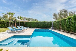 Ein Swimmingpool mit Liegestühlen und einem Strohdachschirm.