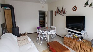 En stue med sofa, bord, tv, pejs og en dør til et andet rum.