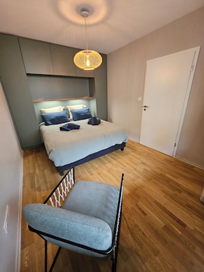 A bedroom with a bed, a chair, a hanging light fixture, and a door. - *L'Avant-Première* Near train station, Pompidou and Arena (Metz)