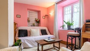 A cozy living room with a sofa, a coffee table, and a window with a view. - Gite "Au Lalli" – Kaysersberg Vignoble: Alsatian Charm in a Renovated 1721 House (Kaysersberg Vignoble)