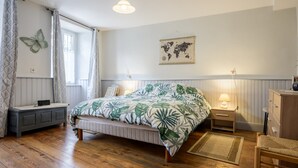 A bedroom with a bed, a nightstand, a dresser, a window with curtains, a world map on the wall, and a hanging light fixture. - Gite "Au Lalli" – Kaysersberg Vignoble: Alsatian Charm in a Renovated 1721 House (Kaysersberg Vignoble)