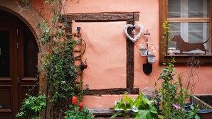 A rustic building with a wooden door, a heart-shaped decoration, and a dog silhouette on the window. - Gite "Au Lalli" – Kaysersberg Vignoble: Alsatian Charm in a Renovated 1721 House (Kaysersberg Vignoble)
