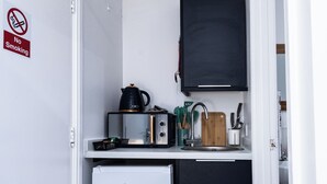 A compact kitchenette with a small fridge, a toaster, a kettle, and a sink. - Guestz at The Wellington (Blackpool)