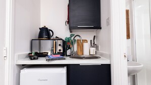 A compact kitchenette with a fridge, a kettle, a toaster, a sink, and a cabinet. - Guestz at The Wellington (Blackpool)