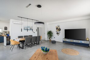 Ein modernes Wohnzimmer mit Essbereich, einem Flachbildfernseher und einer Topfpflanze.