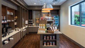 L'intérieur d'un café moderne, avec une machine à café, des étagères remplies de produits emballés et une vue sur l'extérieur par la fenêtre.