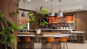 Un espace bar moderne doté d’un îlot central, de tabourets de bar, de luminaires suspendus et d’un mur en briques en arrière-plan.