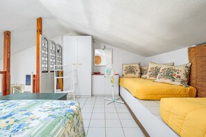 Ein Zimmer mit Bett, Schreibtisch, Stuhl, Ventilator und Kleiderschrank.