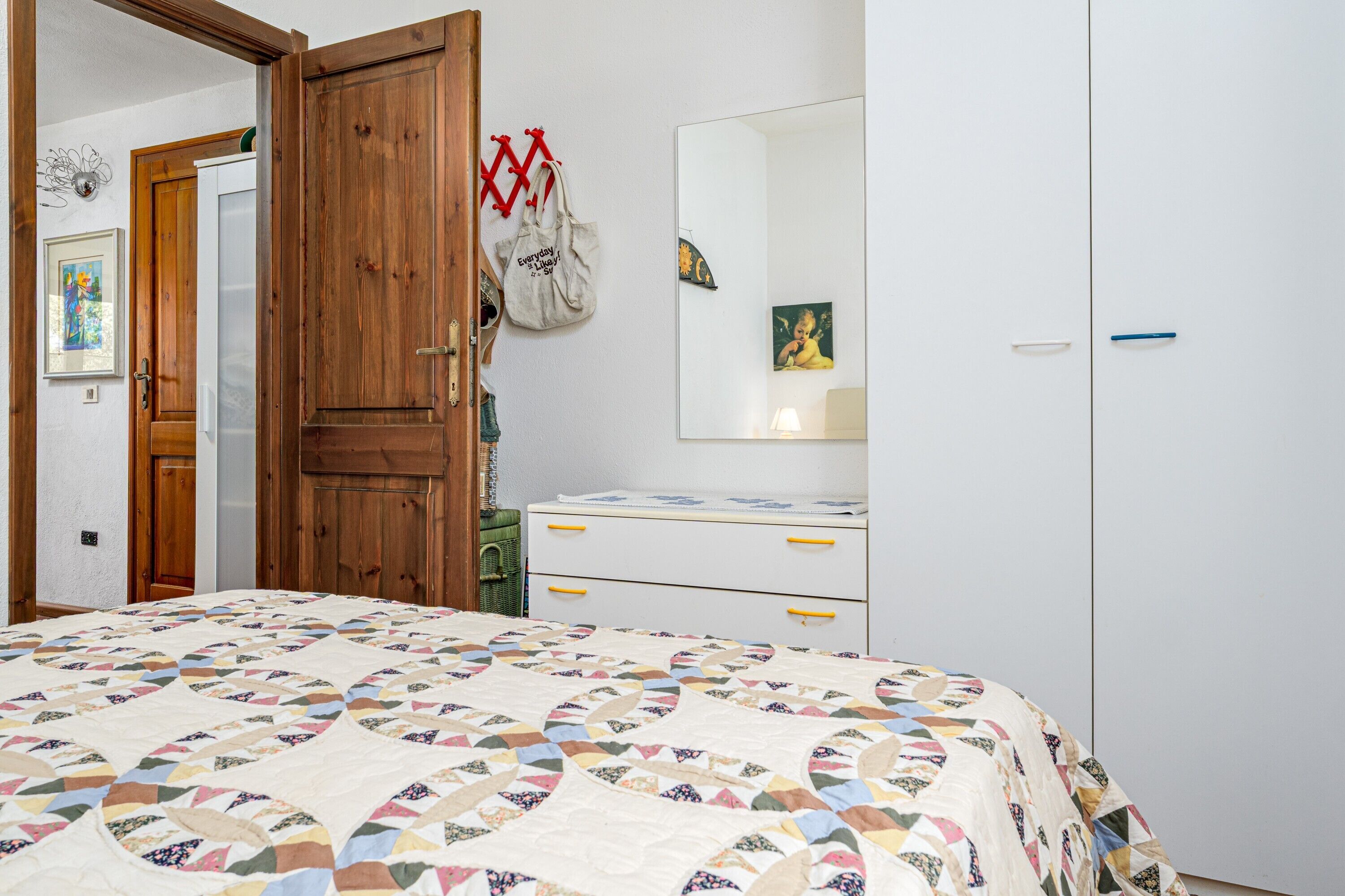 A bedroom with a bed, a dresser, a mirror, and a door.