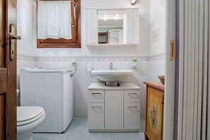 Ein Badezimmer mit Toilette, Waschmaschine, Waschbecken und Schrank.