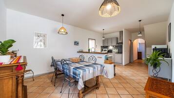 Uma área de refeições com mesa, cadeiras e luminárias pendentes.