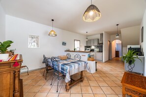 A dining area with a table, chairs, and hanging pendant lights.