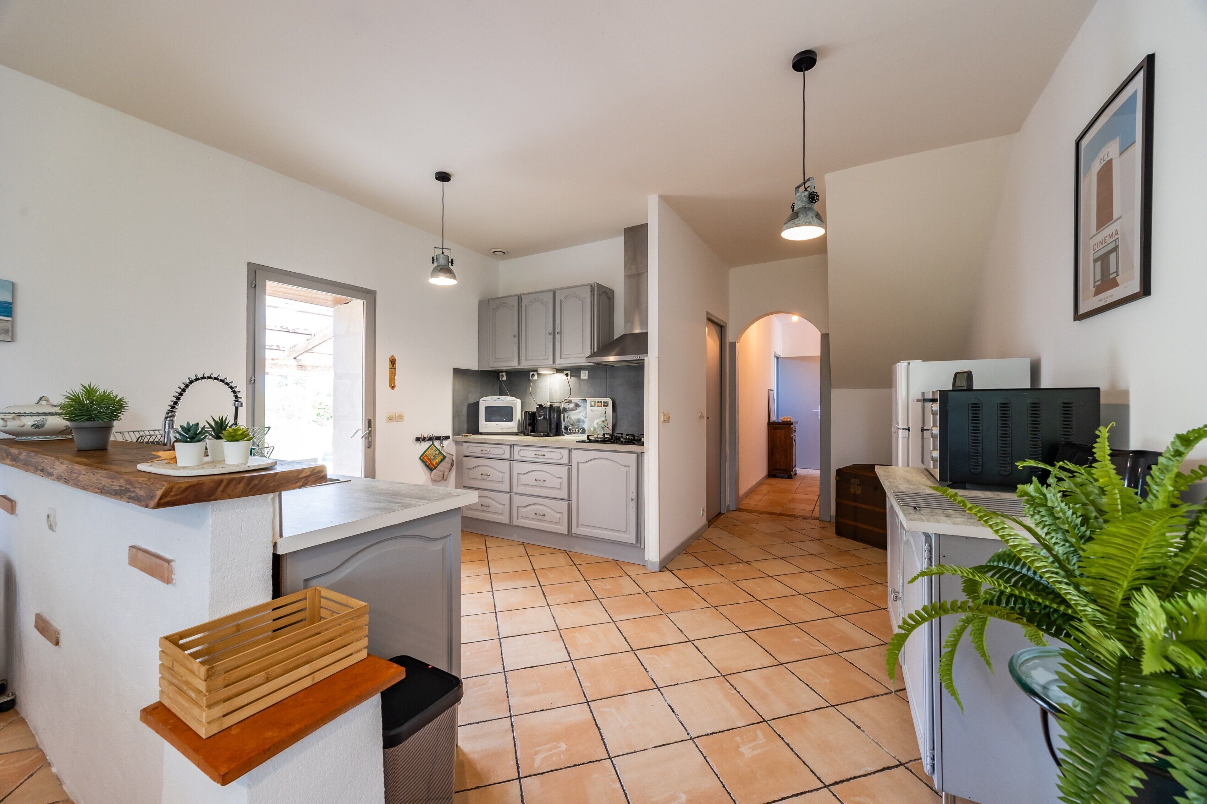 A modern kitchen with white cabinets, a wooden countertop, and a tiled floor.