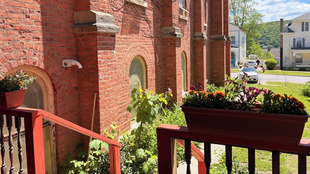 Un edificio de ladrillo rojo con una escalera de madera y plantas en macetas.