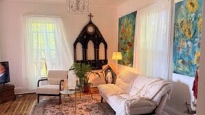 Una sala de estar con sofá, sillón, televisor, candelabro y obras de arte.