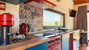 Eine Küche mit einem roten Herd, einer Kaffeemaschine und einem Fenster mit Blick.