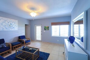 A room with a ceiling fan, two wicker chairs with cushions, a glass coffee table, a white cabinet, and a large mirror. - Fantastic 4bedroom/4bath private home on beautiful Chalk Sound. (Providenciales)