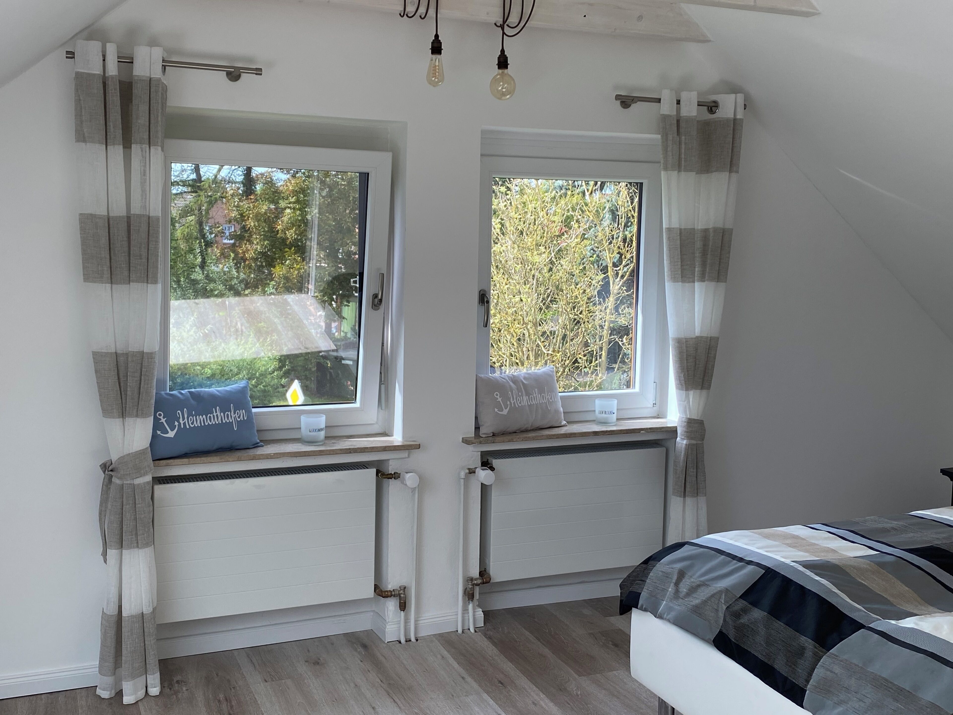 A bedroom with two windows, a radiator, and a bed.