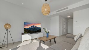 Ein modernes Wohnzimmer mit einer Couch, einem Couchtisch, einem Fernseher und einer Wandlampe.