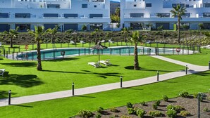 Ein modernes Hotel mit Schwimmbad, Liegestühlen und einem gepflegten Rasen.