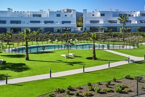 Ein modernes Hotel mit Schwimmbad, Liegestühlen und einem gepflegten Rasen.