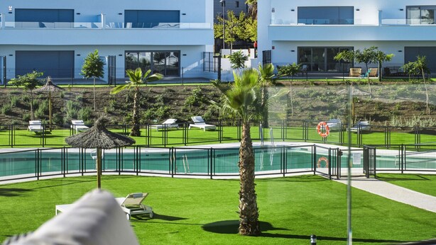 Ein modernes Hotel mit Schwimmbad, Liegestühlen und Palmen.
