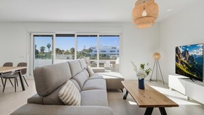 Ein modernes Wohnzimmer mit einer Couch, einem Holztisch und einem großen Fernseher.