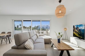 Ein modernes Wohnzimmer mit einer Couch, einem Holztisch und einem großen Fernseher.