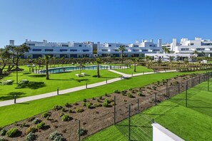 Ein modernes Hotel mit Pool, grünen Rasenflächen und blauem Himmel.