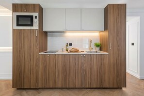 Eine moderne Küche mit Holzschränken, einer eingebauten Mikrowelle, einem Brotlaib und einer kleinen Pflanze.