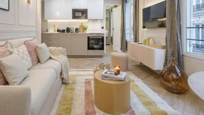 Una sala moderna con un sofá, una mesa de centro y una cocina al fondo.