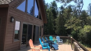 Una cabaña de madera con terraza, ventanas amplias y mobiliario exterior.