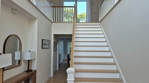 A staircase with white steps and wooden handrails, leading to an upper floor. - Hampton Bays Traditional with a heated pool, plenty of privacy, minutes to... (Hampton bays)