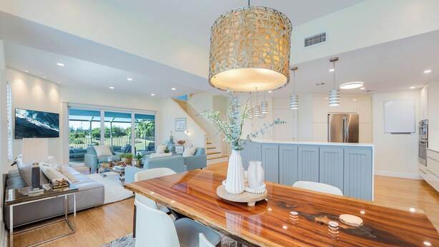Una cocina moderna con una isla de madera, electrodomésticos de acero inoxidable y una lámpara colgante grande.