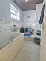 Un baño con bañera, lavamanos, inodoro y espejo.