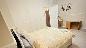 Un dormitorio con cama, escritorio, silla y armario.