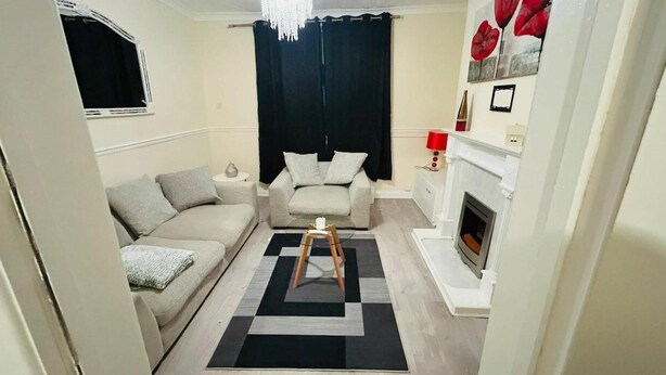 Una sala de estar con sofá, mesa de centro, chimenea y candelabro.