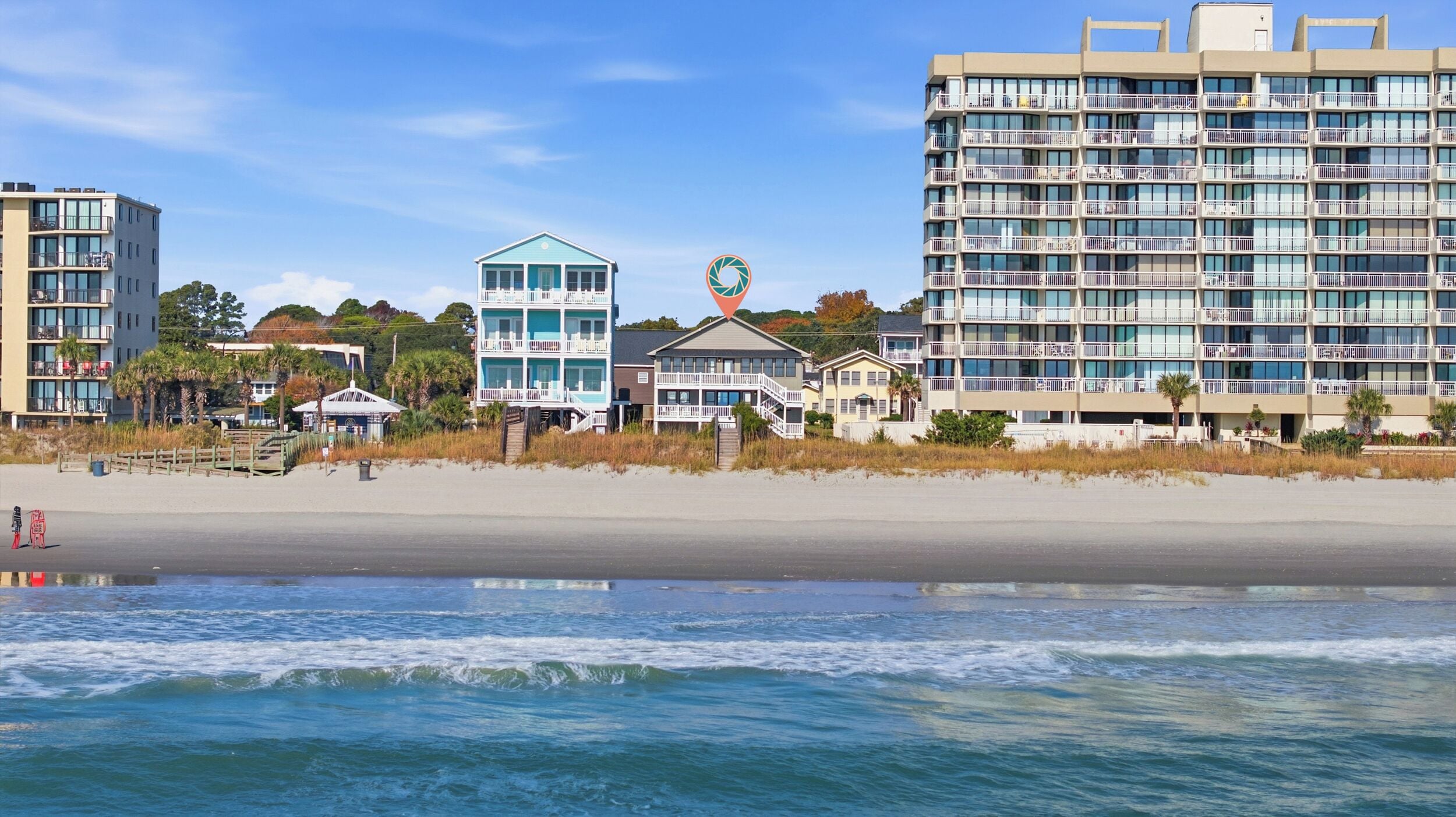 A beachfront hotel with multiple floors, balconies, and a beach view.
