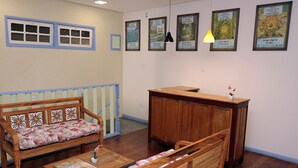 Una habitación con un banco de madera, una mesita con un florero y un armario de madera.
