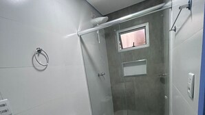 Un baño moderno con cabina de ducha de vidrio, inodoro blanco y encimera de mármol.