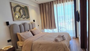 Ein modernes Schlafzimmer mit einem großen Bett, Holzboden, einem geometrischen Teppich und einem Bild an der Wand.