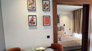 Ein modernes Zimmer mit einem Glastisch, orangefarbenen Stühlen und Bildern an den Wänden.