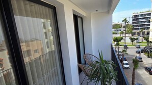 Ein Balkon mit Blumentopf, Stuhl und Blick auf einen Parkplatz sowie Gebäude.