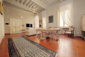 A room with a dining table, chairs, a chandelier, a television, and a fireplace. - Lavish apartment in historical building - Palazzo Boncompagni Corcos (Roma)