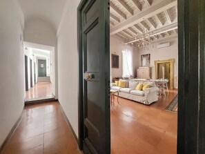 A hallway leading to a living area with a sofa, a chandelier, and a dining table. - Lavish apartment in historical building - Palazzo Boncompagni Corcos (Roma)